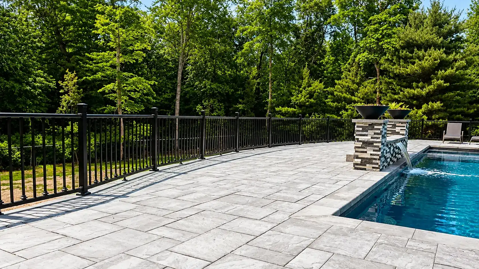 Black aluminum pool code fence around a stone patio pool in Colts Neck NJ