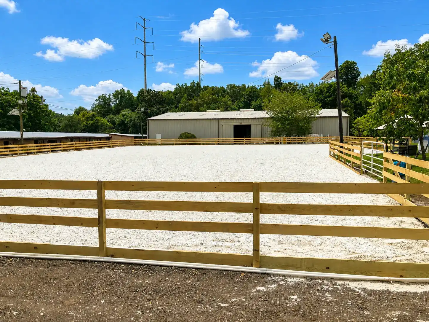 Wood post-and-rail horse paddock fence around a riding arena