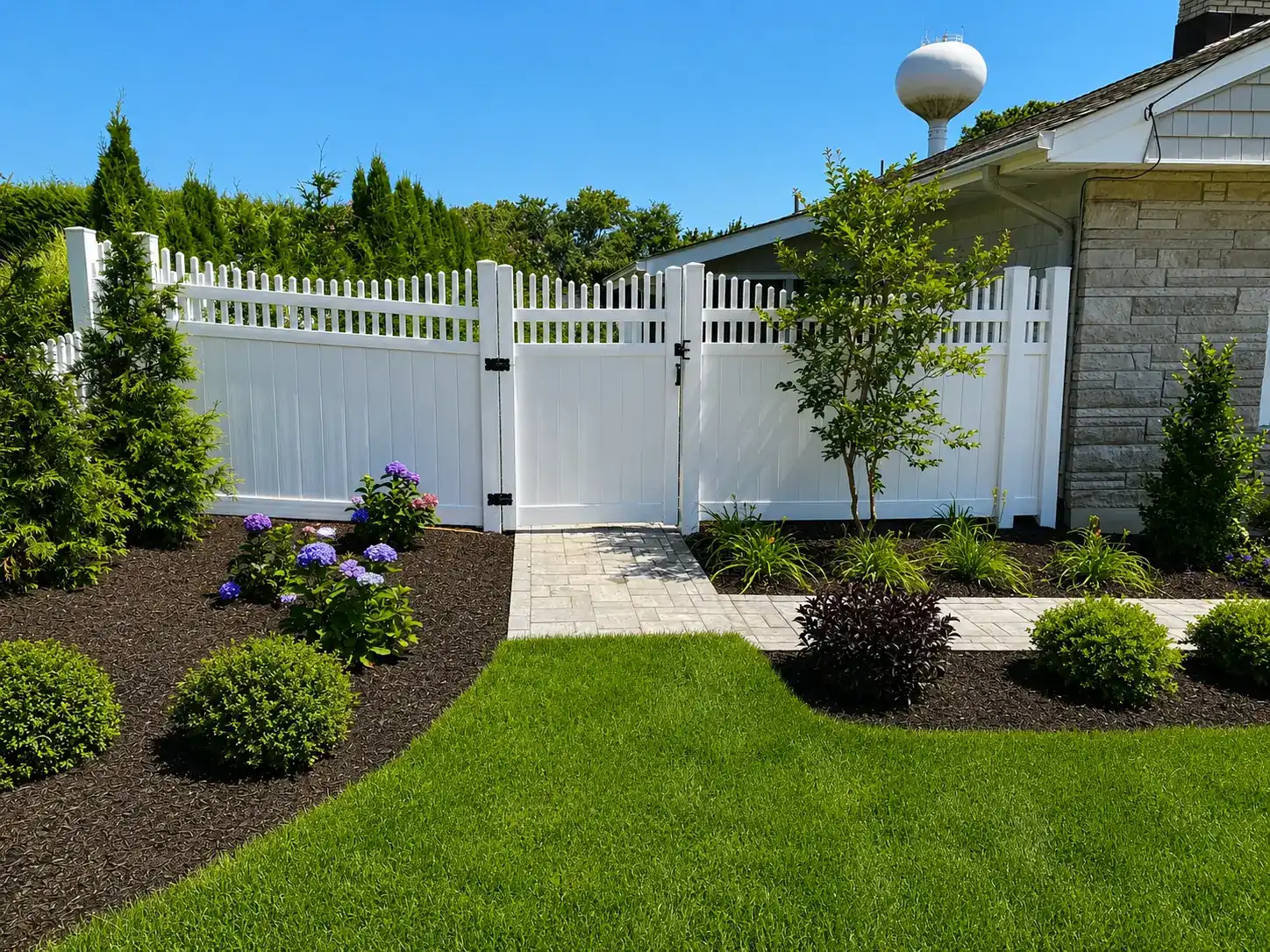 White vinyl picket-top privacy fence with gate and landscaped front yard in Lincroft, NJ
